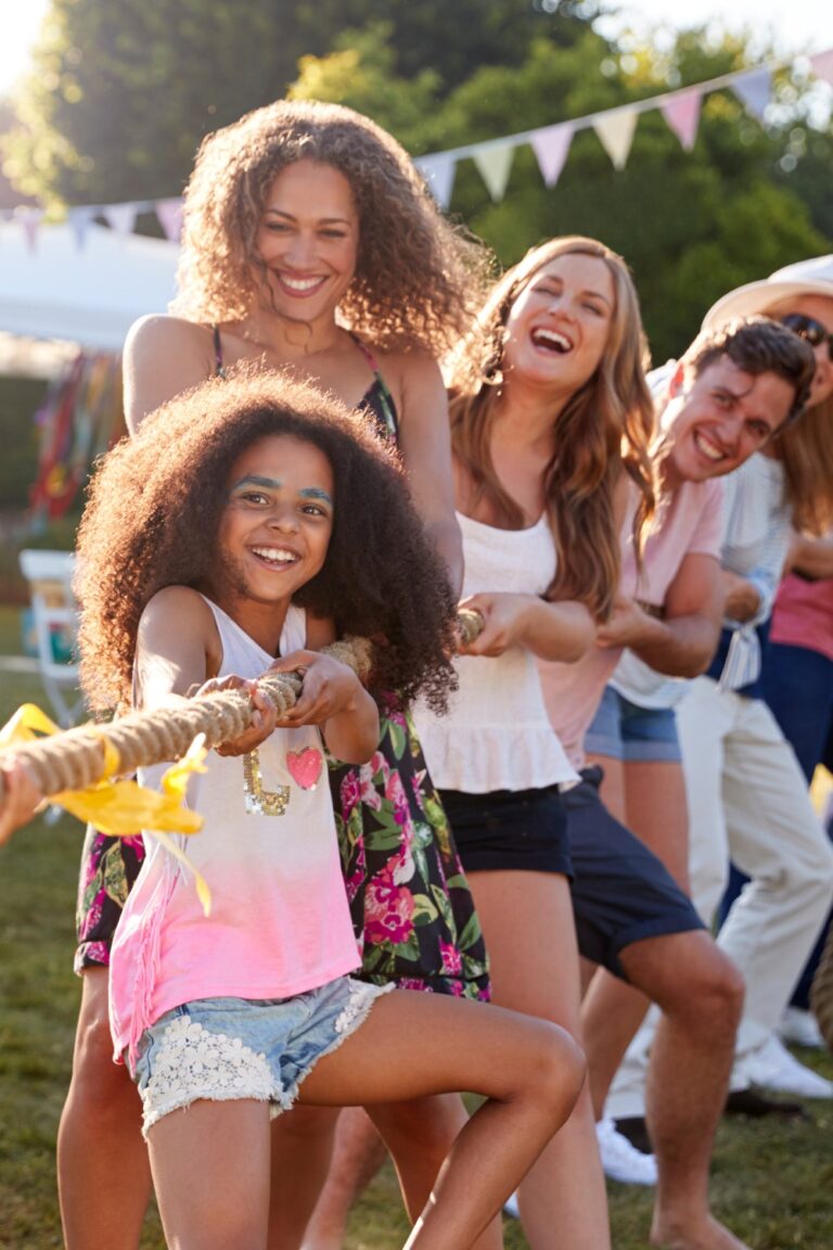 People at a family reunion pulling on a large rope in a game of tug-of-war. Each side has men, women, and children.