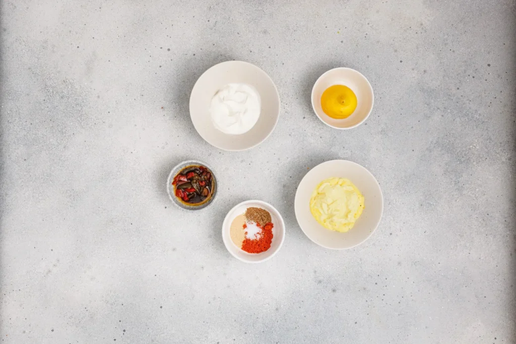 Ingredients for chipotle ranch dressing, including sour cream, mayonnaise, chipotle peppers, lemon, and seasonings.