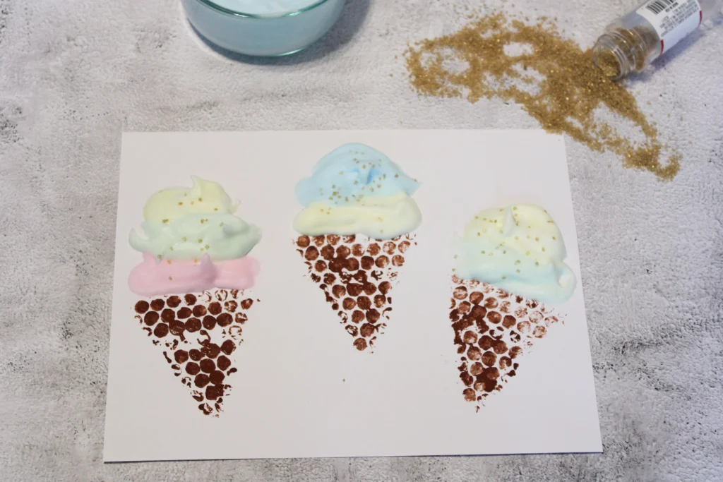 Close-up view of three puffy paint ice cream cones with glitter sprinkles.