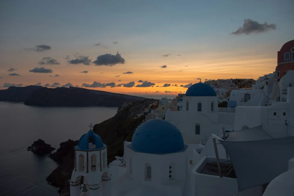 Sunset view of Santorini with white buildings and blue-domed churches overlooking the sea