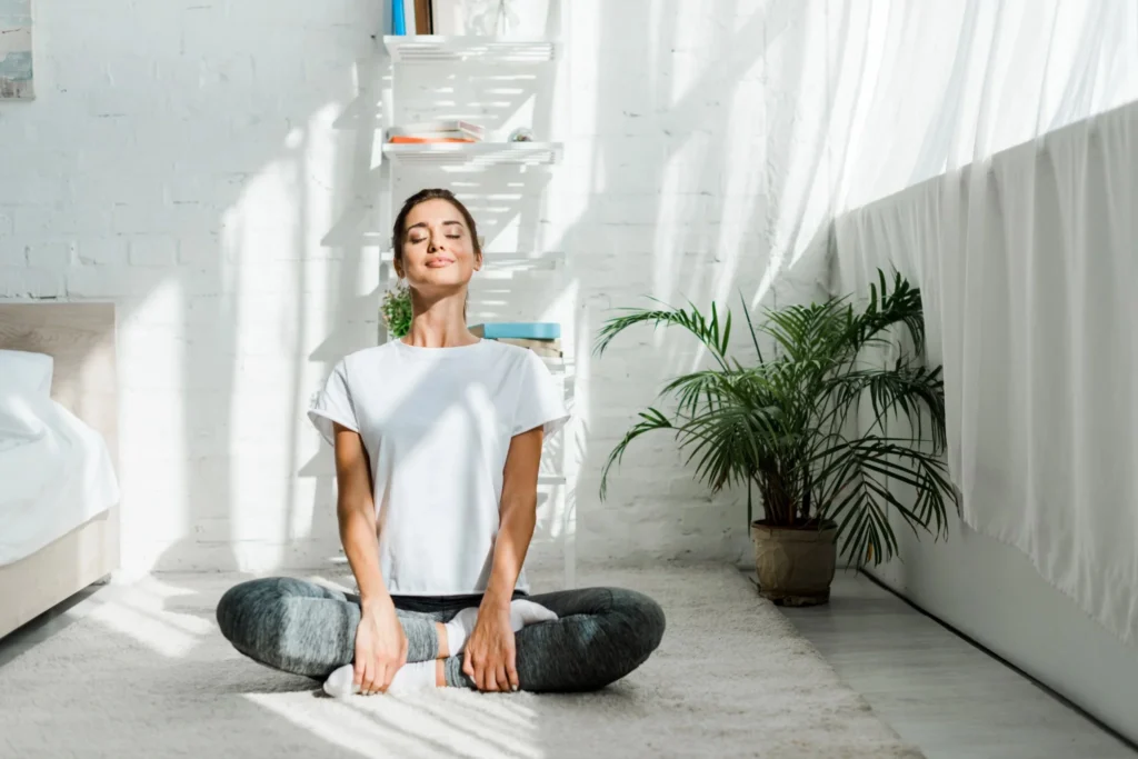 Woman practicing mindfulness and stress reduction while sitting calmly in a bright, peaceful home