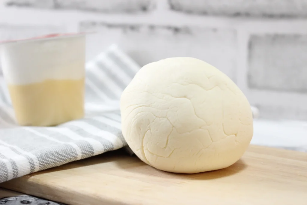 Homemade pudding play dough beside a banana pudding cup and kitchen cloth
