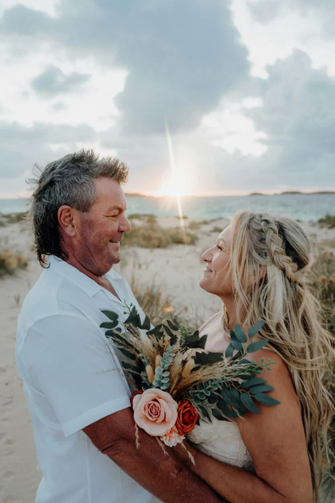 couple holding each other on beach at sunset during vow renewal ceremony