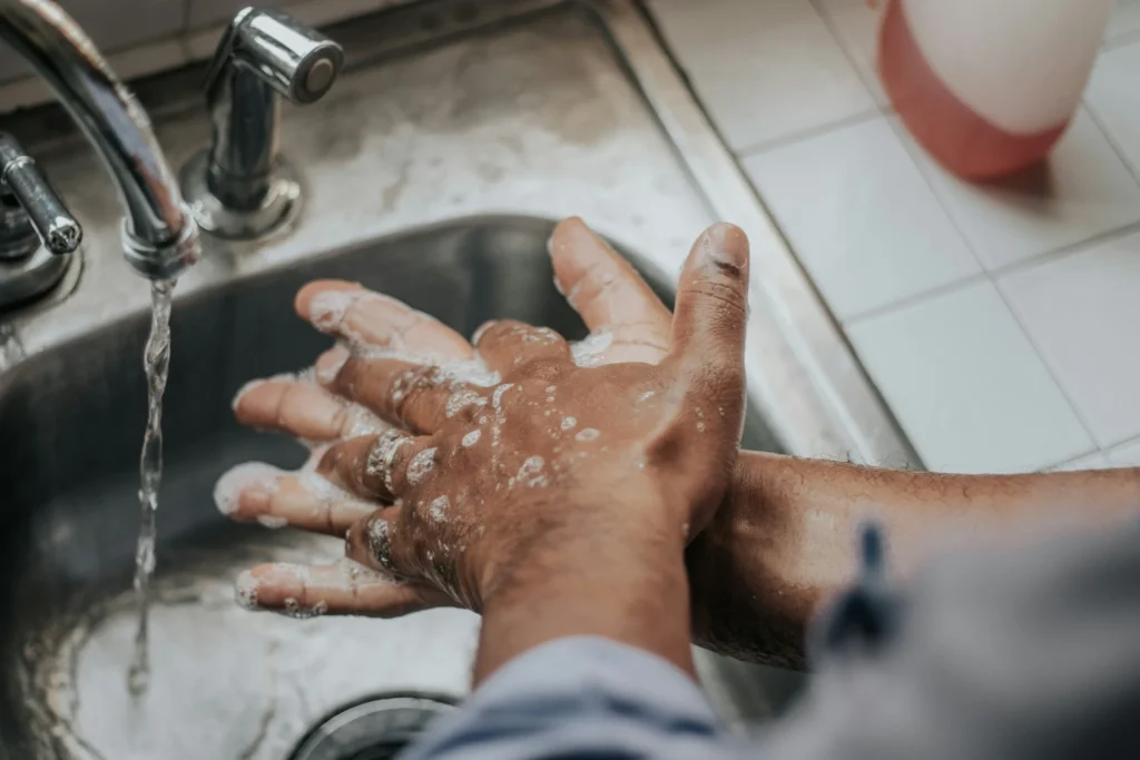Person washing hands with soap under running water to remove allergens and maintain hygiene