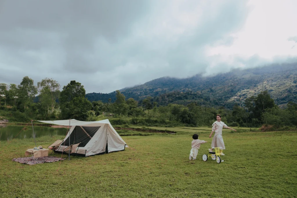 A parent and child enjoying a family camping trip near mountains and open fields.