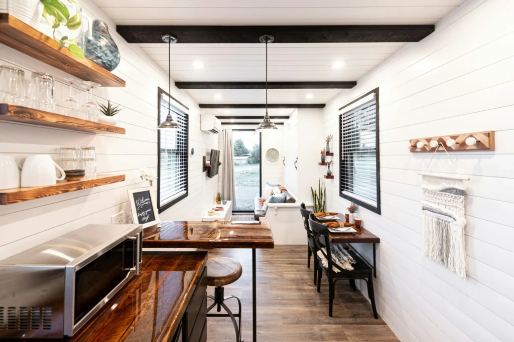 Modern tiny house interior with white shiplap walls and compact dining area.