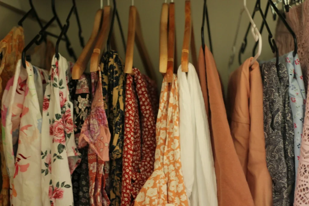 A collection of floral prints, soft neutrals, and lightweight clothing hanging in a closet during a seasonal wardrobe refresh.