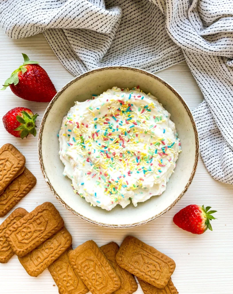 Overhead view of sweet fun confetti dip topped with colorful sprinkles and served with cookies and fresh strawberries.