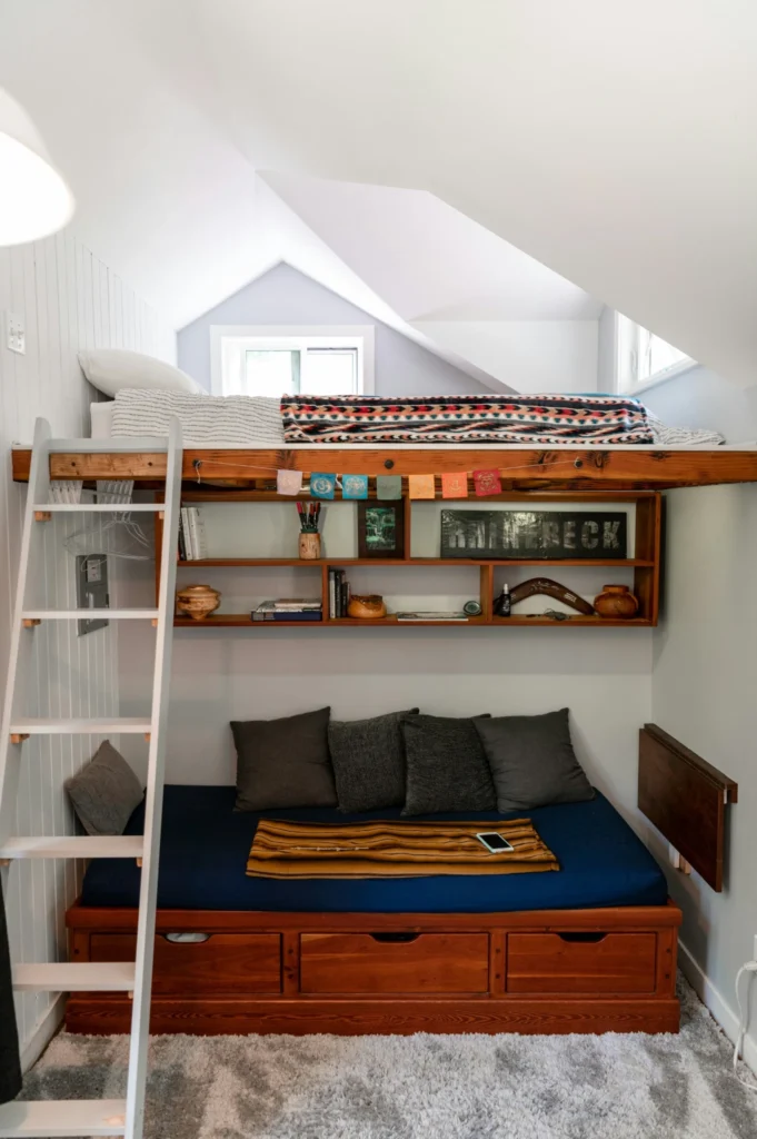 Compact tiny house bedroom with loft bed, built-in shelving, and under-bed storage.