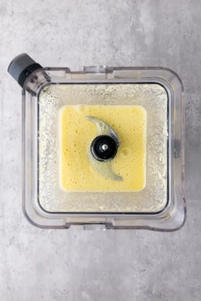 Smooth pineapple coconut lime mixture blended and ready to pour into popsicle molds.