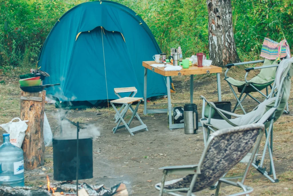 Simple tent campsite setup with camp chairs and cooking equipment for beginner campers.