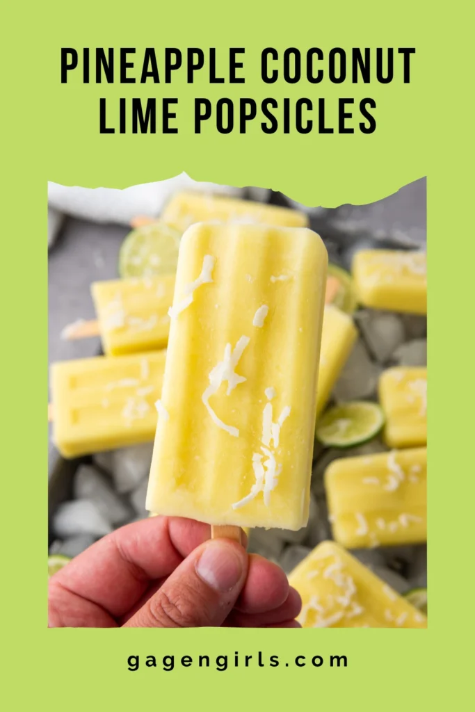 Hand holding a pineapple coconut lime popsicle above a tray of tropical homemade popsicles.