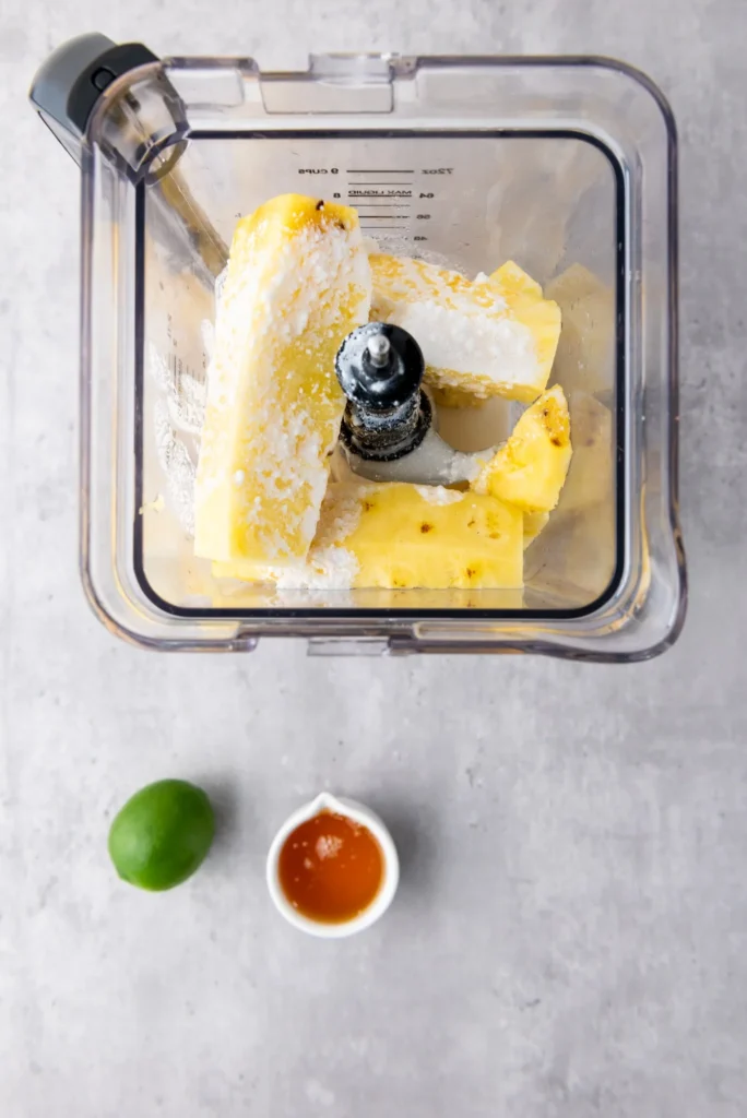 Pineapple chunks and coconut milk in a blender before being blended into popsicle mixture.