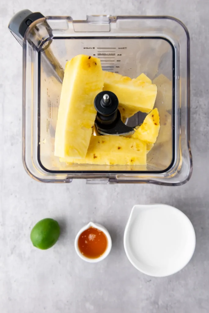 Fresh pineapple chunks placed in a blender for making homemade pineapple coconut lime popsicles.