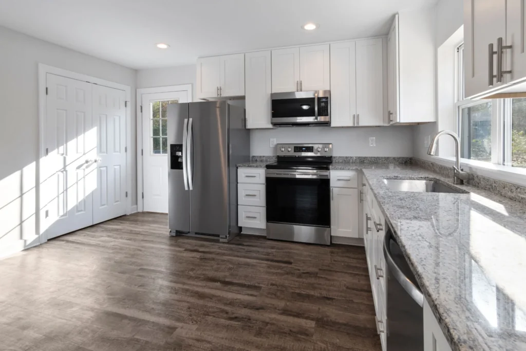 Bright white kitchen remodel with shaker cabinets, granite countertops, and stainless steel appliances.