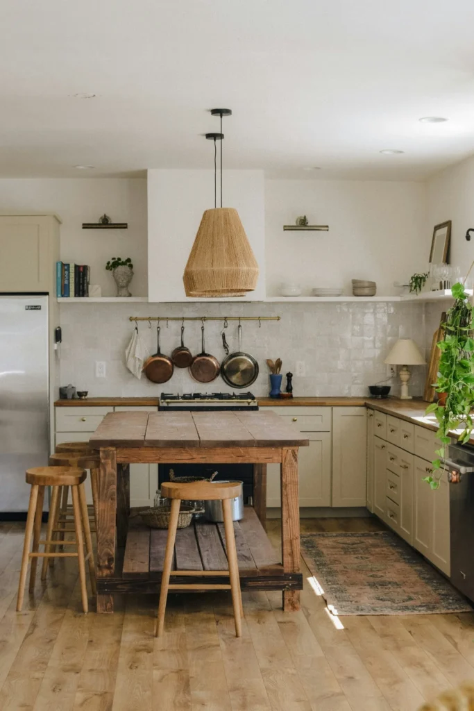 Cozy modern kitchen remodel with wood island, hanging cookware, and warm neutral finishes.