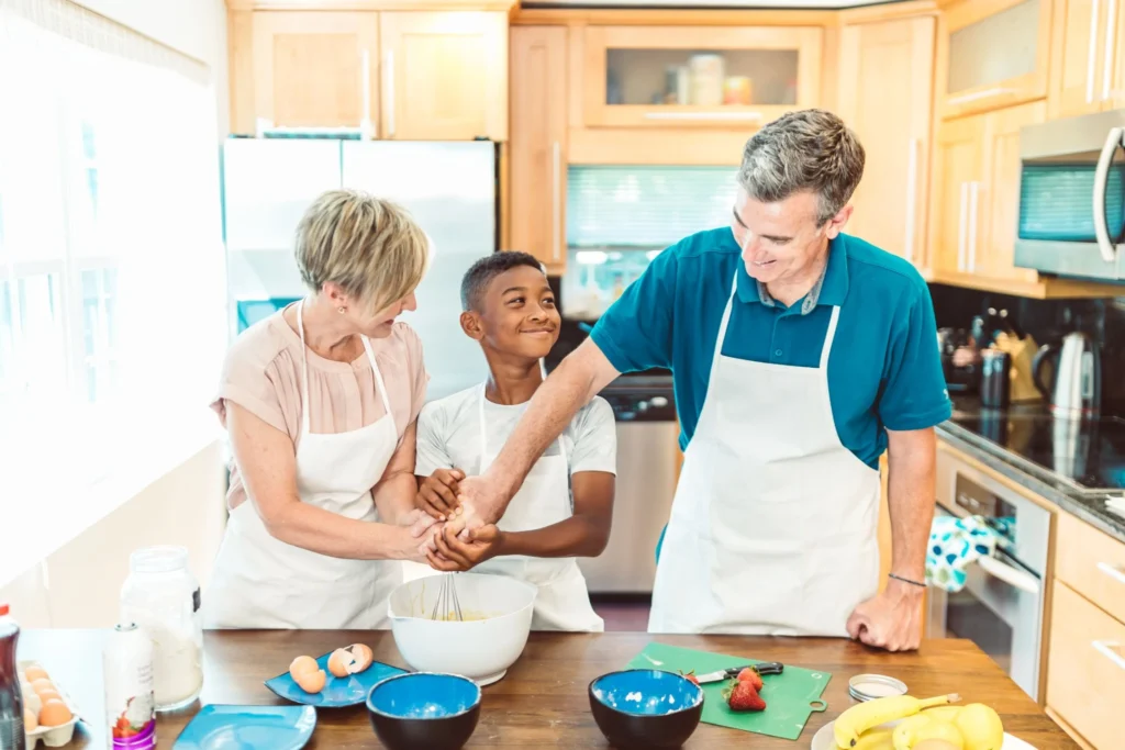 Grandparents and child baking together in the kitchen as a rainy day activity.