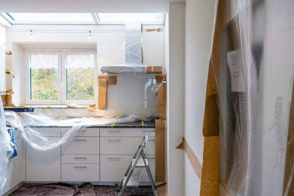 Kitchen remodel in progress with cabinets and countertops covered for protection during construction.