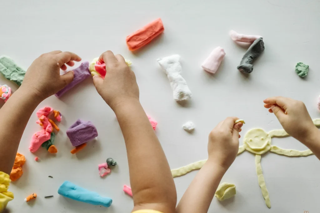 Children creating shapes and pictures with colorful homemade play dough.