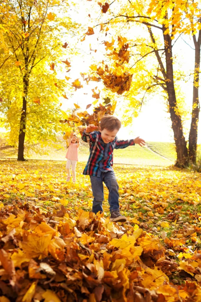 Children playing together in a pile of autumn leaves outdoors