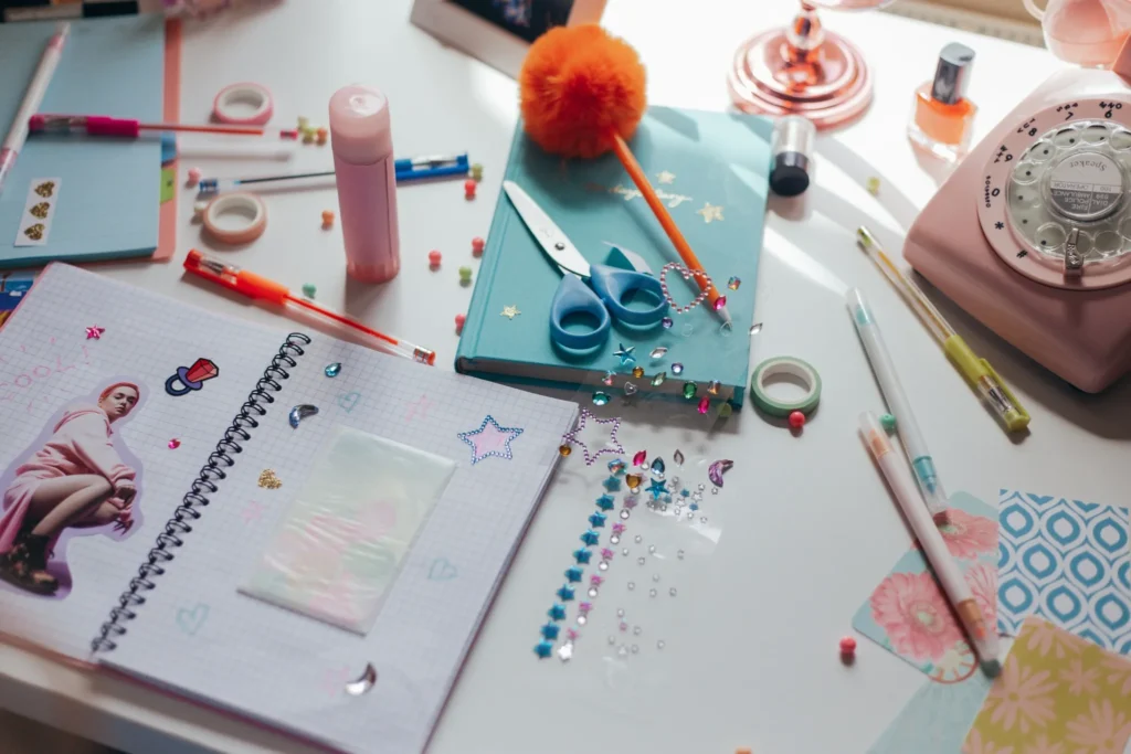 Craft worktable with scissors, notebooks, paper, pens, and colorful supplies