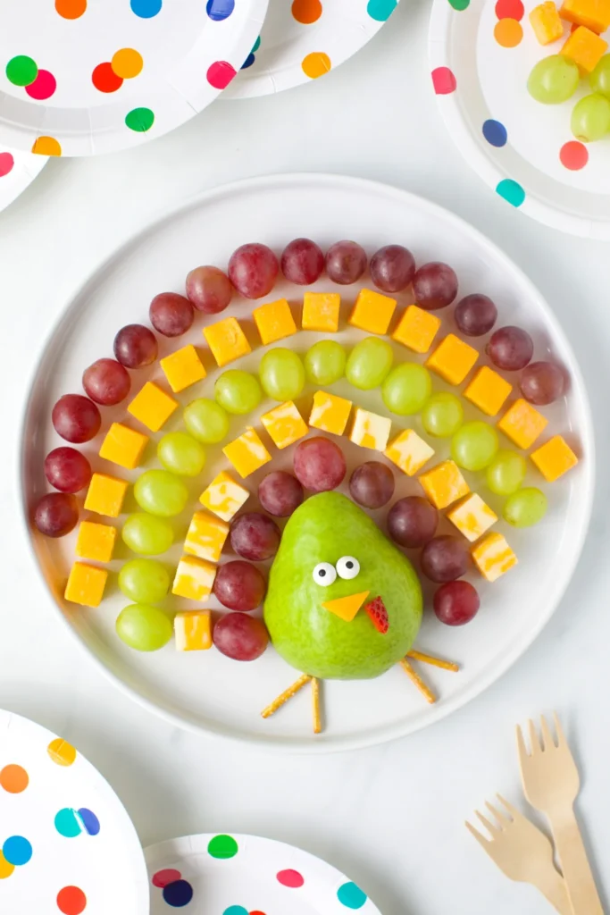 Thanksgiving turkey fruit tray made with red and green grapes, cheese, and a pear